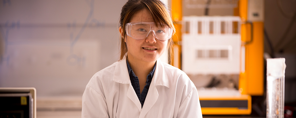 Student in lab wearing lab coat and goggles